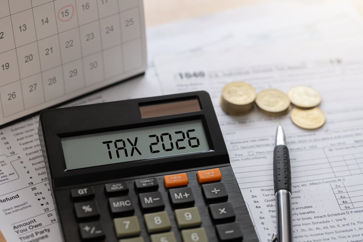 Calculadora, calendario y monedas sobre un escritorio para planear impuestos